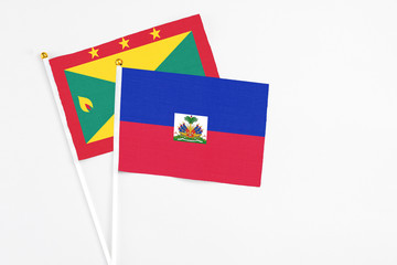 Haiti and Grenada stick flags on white background. High quality fabric, miniature national flag. Peaceful global concept.White floor for copy space.