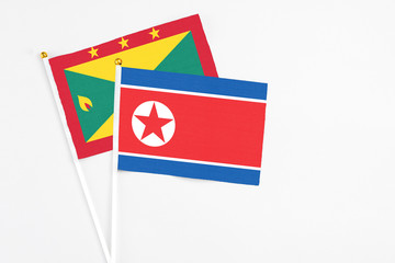 North Korea and Grenada stick flags on white background. High quality fabric, miniature national flag. Peaceful global concept.White floor for copy space.