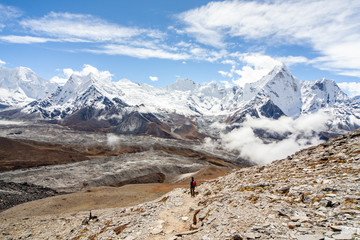 A man Walking down Chukhung Ri mountain with the Ama Dablam peak in the back and other summit on the 3 passes trek in the everest region, Nepal