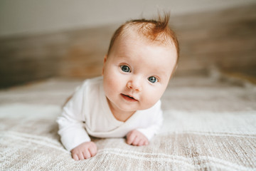 Cute baby ginger hair close up crawling on bed smiling adorable kid portrait family lifestyle 3 month old child - obrazy, fototapety, plakaty