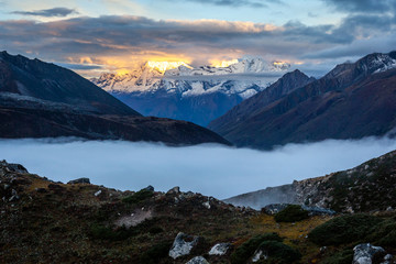 sunrise lighting mountain peaks of the himalaya with clouds under in Chukhung on the 3 passes trek