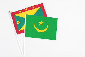 Mauritania and Grenada stick flags on white background. High quality fabric, miniature national flag. Peaceful global concept.White floor for copy space.