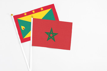 Morocco and Grenada stick flags on white background. High quality fabric, miniature national flag. Peaceful global concept.White floor for copy space.