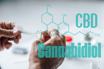 cropped view of man holding blunt of medical cannabis with cbd molecule illustration