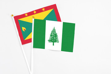 Norfolk Island and Grenada stick flags on white background. High quality fabric, miniature national flag. Peaceful global concept.White floor for copy space.