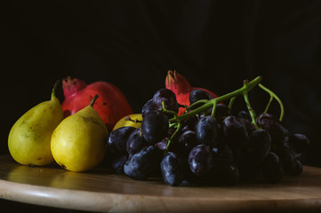 still life pears and black grapes on a black background