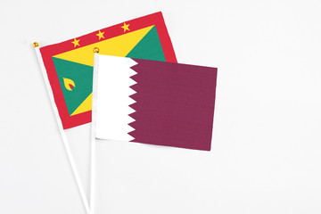 Qatar and Grenada stick flags on white background. High quality fabric, miniature national flag. Peaceful global concept.White floor for copy space.