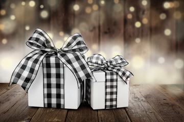 Rustic Christmas gifts with black and white buffalo plaid check ribbon. Side view with a dark wood...