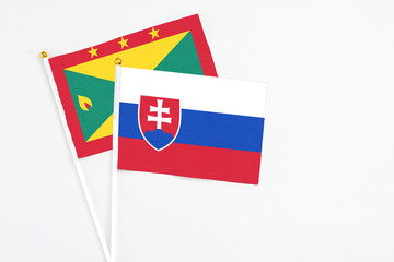 Slovakia and Grenada stick flags on white background. High quality fabric, miniature national flag. Peaceful global concept.White floor for copy space.