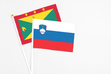 Slovenia and Grenada stick flags on white background. High quality fabric, miniature national flag. Peaceful global concept.White floor for copy space.
