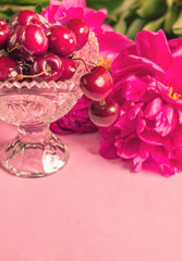Obraz na płótnie Canvas Cherries in the beautiful crystal vase with peony