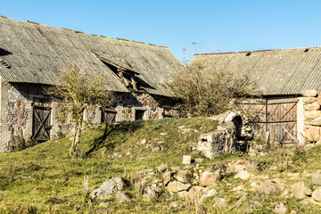 Fototapeta na wymiar Autumn. Old abandoned barns. A stone cellar in the foreground. . Former dairy industry. Podlasie, Poland.
