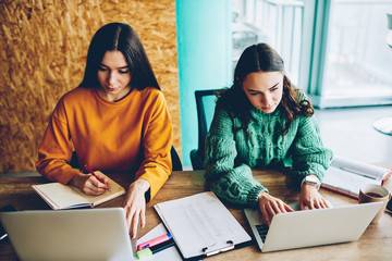 Skilled students doing homework at modern netbook sitting in college interior.Smart female designers using high speed 4G internet connection for remote work at digital laptop computer