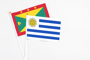 Uruguay and Grenada stick flags on white background. High quality fabric, miniature national flag. Peaceful global concept.White floor for copy space.