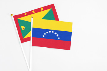Venezuela and Grenada stick flags on white background. High quality fabric, miniature national flag. Peaceful global concept.White floor for copy space.