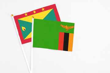 Fototapeta premium Zambia and Grenada stick flags on white background. High quality fabric, miniature national flag. Peaceful global concept.White floor for copy space.