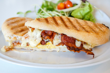 Close up of sandwich toast grilled with bacon and cheese on white plate