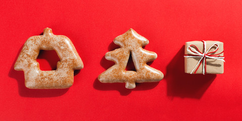 Christmas gingerbread cookies in the shape of a Christmas tree and craft gifts on a red background, copy space.
