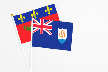 Anguilla and Guadeloupe stick flags on white background. High quality fabric, miniature national flag. Peaceful global concept.White floor for copy space.