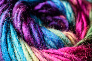 Closeup of deep rich jewel tone rainbow variegated skein of yarn