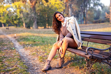 Beautiful young woman sitting on bench in park and smile