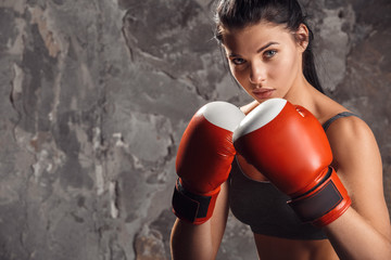 Boxing. Woman boxer in gloves standing isolated on wall ready to kick confident