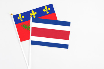 Costa Rica and Guadeloupe stick flags on white background. High quality fabric, miniature national flag. Peaceful global concept.White floor for copy space.