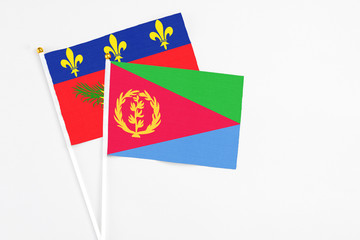 Eritrea and Guadeloupe stick flags on white background. High quality fabric, miniature national flag. Peaceful global concept.White floor for copy space.