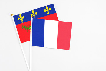 France and Guadeloupe stick flags on white background. High quality fabric, miniature national flag. Peaceful global concept.White floor for copy space.