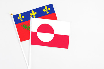 Greenland and Guadeloupe stick flags on white background. High quality fabric, miniature national flag. Peaceful global concept.White floor for copy space.