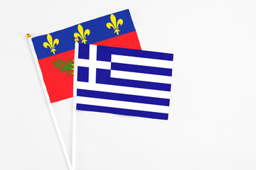 Greece and Guadeloupe stick flags on white background. High quality fabric, miniature national flag. Peaceful global concept.White floor for copy space.