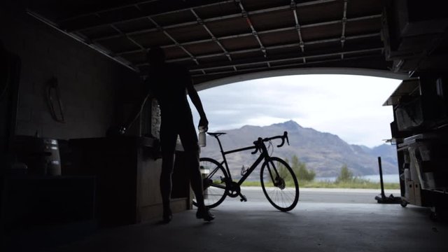 Silhouette of male cyclist servicing bicycle Lake Wakatipu