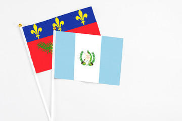 Guatemala and Guadeloupe stick flags on white background. High quality fabric, miniature national flag. Peaceful global concept.White floor for copy space.