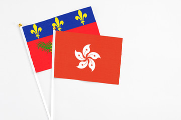 Hong Kong and Guadeloupe stick flags on white background. High quality fabric, miniature national flag. Peaceful global concept.White floor for copy space.