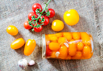 Glass jars with homemade pickled tomatoes, sealed with metal lid