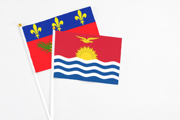 Kiribati and Guadeloupe stick flags on white background. High quality fabric, miniature national flag. Peaceful global concept.White floor for copy space.