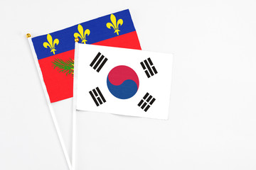 South Korea and Guadeloupe stick flags on white background. High quality fabric, miniature national flag. Peaceful global concept.White floor for copy space.