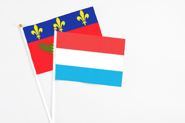 Luxembourg and Guadeloupe stick flags on white background. High quality fabric, miniature national flag. Peaceful global concept.White floor for copy space.
