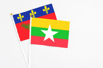 Myanmar and Guadeloupe stick flags on white background. High quality fabric, miniature national flag. Peaceful global concept.White floor for copy space.