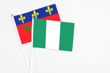 Nigeria and Guadeloupe stick flags on white background. High quality fabric, miniature national flag. Peaceful global concept.White floor for copy space.