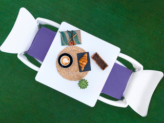 Isolated Aerial View of White table with two chairs and coffee cup and croissant on table , with coffee beans décor , agenda and flower. 