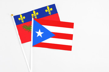 Puerto Rico and Guadeloupe stick flags on white background. High quality fabric, miniature national flag. Peaceful global concept.White floor for copy space.