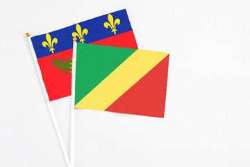 Republic Of The Congo and Guadeloupe stick flags on white background. High quality fabric, miniature national flag. Peaceful global concept.White floor for copy space.