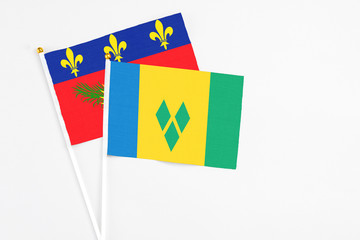 Saint Vincent And The Grenadines and Guadeloupe stick flags on white background. High quality fabric, miniature national flag. Peaceful global concept.White floor for copy space.