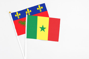 Fototapeta premium Senegal and Guadeloupe stick flags on white background. High quality fabric, miniature national flag. Peaceful global concept.White floor for copy space.