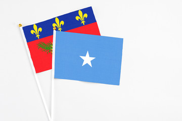 Somalia and Guadeloupe stick flags on white background. High quality fabric, miniature national flag. Peaceful global concept.White floor for copy space.