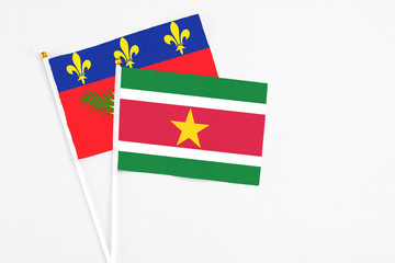 Suriname and Guadeloupe stick flags on white background. High quality fabric, miniature national flag. Peaceful global concept.White floor for copy space.