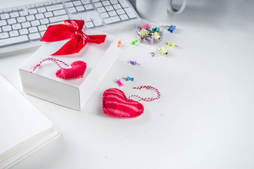 Valentine day concept. Secret Valentine office game idea. February 14 holiday background with gift box, textile hearts and office supplies, white keyboard, notepad. White table background copy space