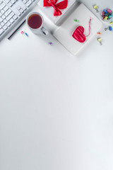 Fototapeta na wymiar Valentine day concept. Secret Valentine office game idea. February 14 holiday background with gift box, textile hearts and office supplies, white keyboard, notepad. White table background copy space