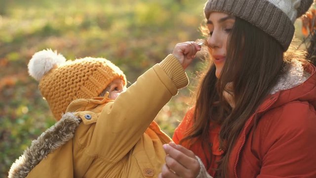 Mom with daughter in knitted hats. Little girl show her mother autumn leaf